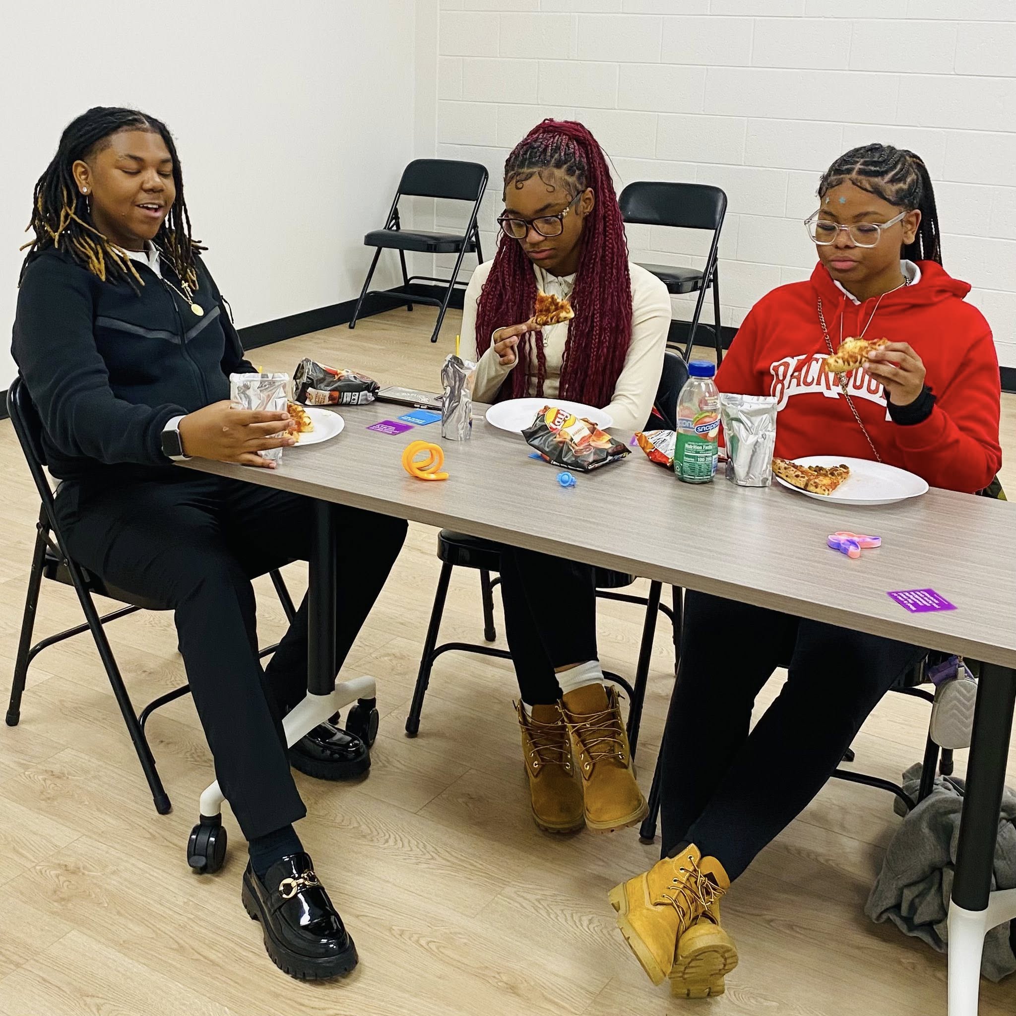 Three teens eating at a table.